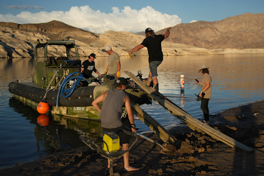 Dave Kiley, also known as Diesel Dave, boards a boat while helping to free a beached houseboat with the crew from the Youtube channel HeavyDSparks at the Lake Mead National Recreation Area, Thursday, June 23, 2022, near Boulder City, Nev. The crew of the Youtube channel hauled a houseboat stranded by falling water levels back into the water.